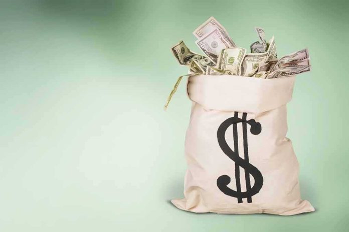 shutterstock_1683634993 Money bag overflowing with US dollar bills on green background