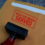 Rubber stamp on manila envelope with red served notice