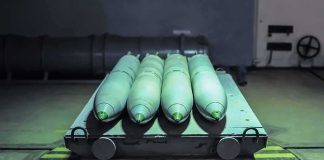 Green missiles on a wheeled cart in an industrial bay