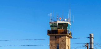 Airport control tower behind chain-link and barbed-wire fence