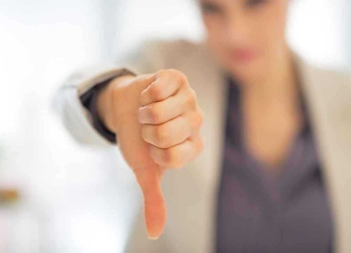 shutterstock_192038057 Businesswoman showing a thumbs down gesture in an office setting