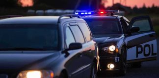 Police car with flashing lights behind a stopped vehicle at dusk