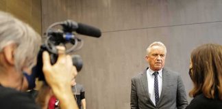 Man in a gray suit speaks to a reporter during an interview