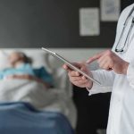 Doctor using tablet beside hospital patient