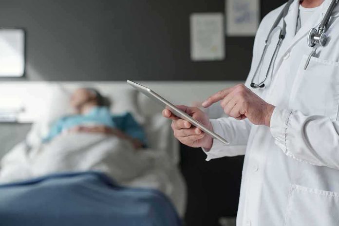 shutterstock_2316812635 Doctor using tablet beside hospital patient