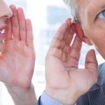 woman whispering to man who cups his ear