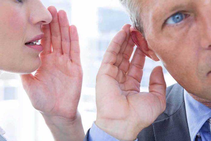 shutterstock_294787076 woman whispering to man who cups his ear