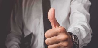 Hand giving a thumbs-up gesture in business attire