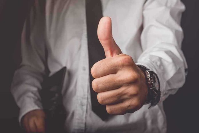 shutterstock_328402811 Hand giving a thumbs-up gesture in business attire