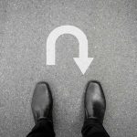 Dem Senator’s SHOCKING Filibuster FLIP! Feet in black shoes facing a U-turn arrow on asphalt