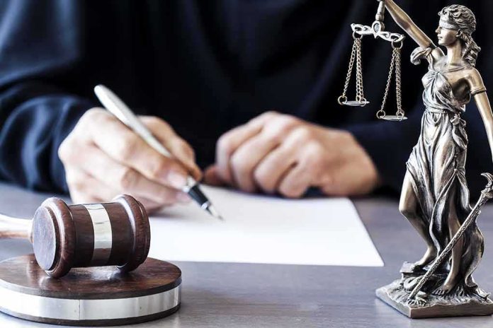 shutterstock_565403533-1 Judge writing at desk with gavel and Lady Justice statue