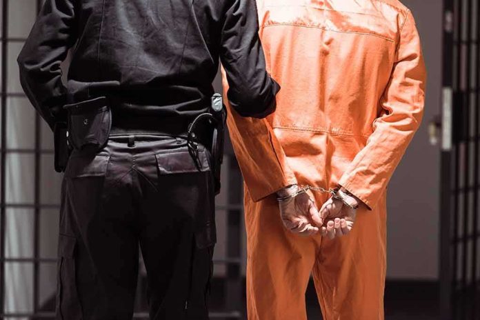 Prisoner in orange jumpsuit handcuffed with guard standing beside