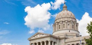 Neoclassical capitol building with large dome and columns under a blue sky