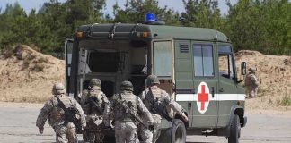 Soldiers carry a wounded comrade on a stretcher to a military ambulance