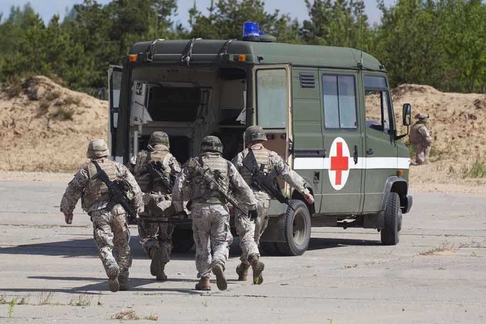 shutterstock_105071369 Soldiers carry a wounded comrade on a stretcher to a military ambulance