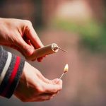 Hands lighting a firework fuse with a match