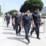 Police officers walking in formation on a city sidewalk