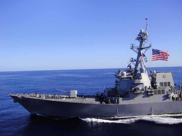 shutterstock_1133692649-1 Naval destroyer sailing on open sea with flag flying