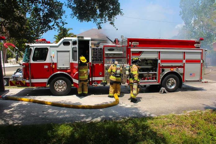 shutterstock_1149745991 Fire truck with firefighters operating hoses on a residential street
