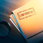 Confidential folder on desk with magnifying glass