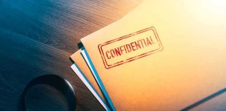 Confidential folder on desk with magnifying glass