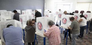 Voters fill out ballots at polling booths in a busy voting room