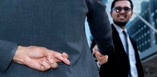 Businessman crosses fingers behind back during handshake