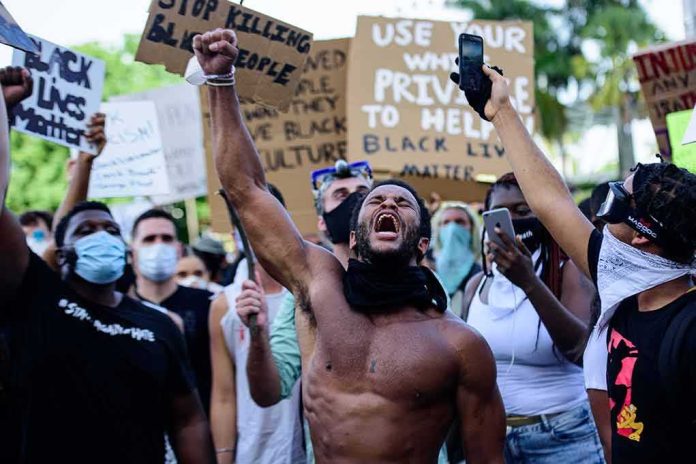 Shirtless protester raises fist while crowd holds signs