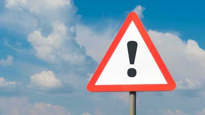 shutterstock_1783780781 Warning road sign with exclamation mark against blue sky