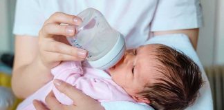 Newborn baby drinking from a bottle while being held