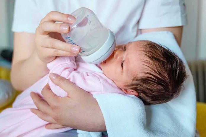 Newborn baby drinking from a bottle while being held