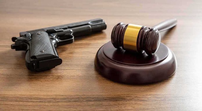 shutterstock_2135622443 Judge's gavel and handgun on wooden table