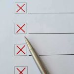 Checklist with red X marks and a silver pen