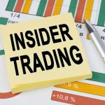 Sticky note reading INSIDER TRADING on financial charts with a pen