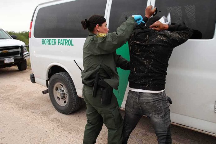 shutterstock_2265137295 Border patrol agent detains a person against a van