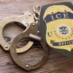 An ICE Agent Shot Into A Home — Look Who Just Put Him In CUFFS ICE officer badge and handcuffs on wooden surface