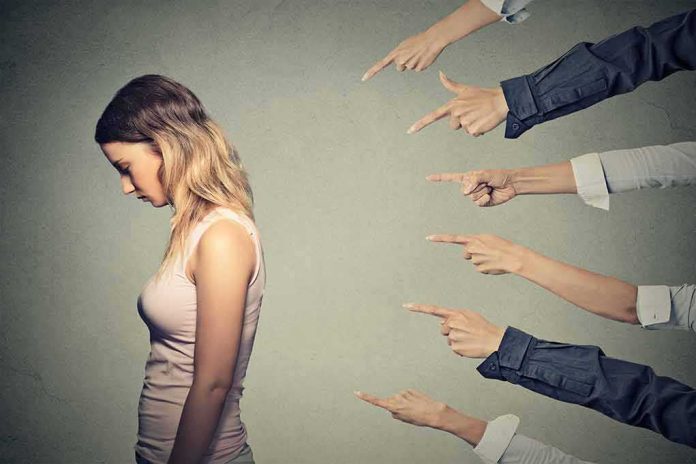 shutterstock_296799968 Young woman looking down while multiple hands point at her
