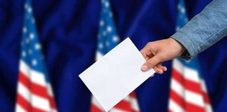 Hand casting ballot into box with U.S. flags in background