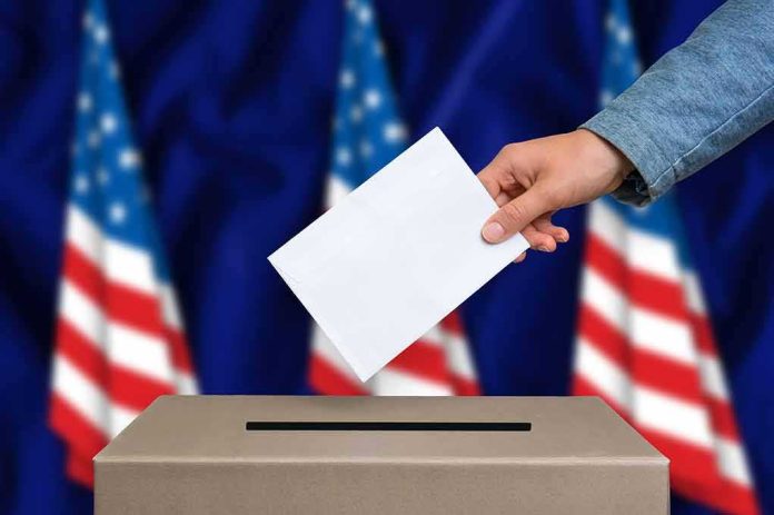 shutterstock_495494674 Hand casting ballot into box with U.S. flags in background