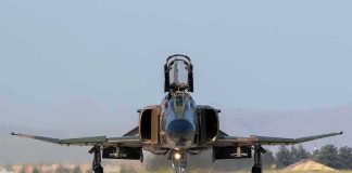 Military jet taxiing on runway with open canopy