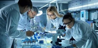 Scientists collaborating in a laboratory around a microscope