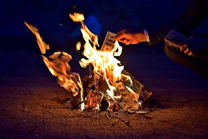 Hands burning cash over a small fire at night