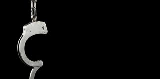She Never Got To See 40 — The Man Who Killed Her Is Getting OUT Open metal handcuff hanging against a black background