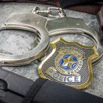 DA Says Cop INVENTED A Killer — And Names His REASON Handcuffs, officer badge, and firearm on textured surface.