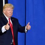Crowd Roars As Trump Erases Convictions Donald Trump giving two thumbs up in front of a blue curtain