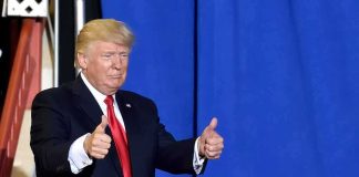 Crowd Roars As Trump Erases Convictions Donald Trump giving two thumbs up in front of a blue curtain