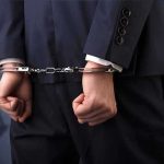 Businessperson in handcuffs with hands behind back