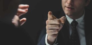 Man in suit pointing a finger during a tense conversation