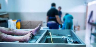cadaver on stainless autopsy table in clinical room