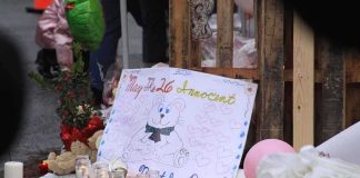 He PROTECTED His Baby Sister — Her Fate Will MOVE You A memorial site with candles, flowers, and a hand-drawn poster